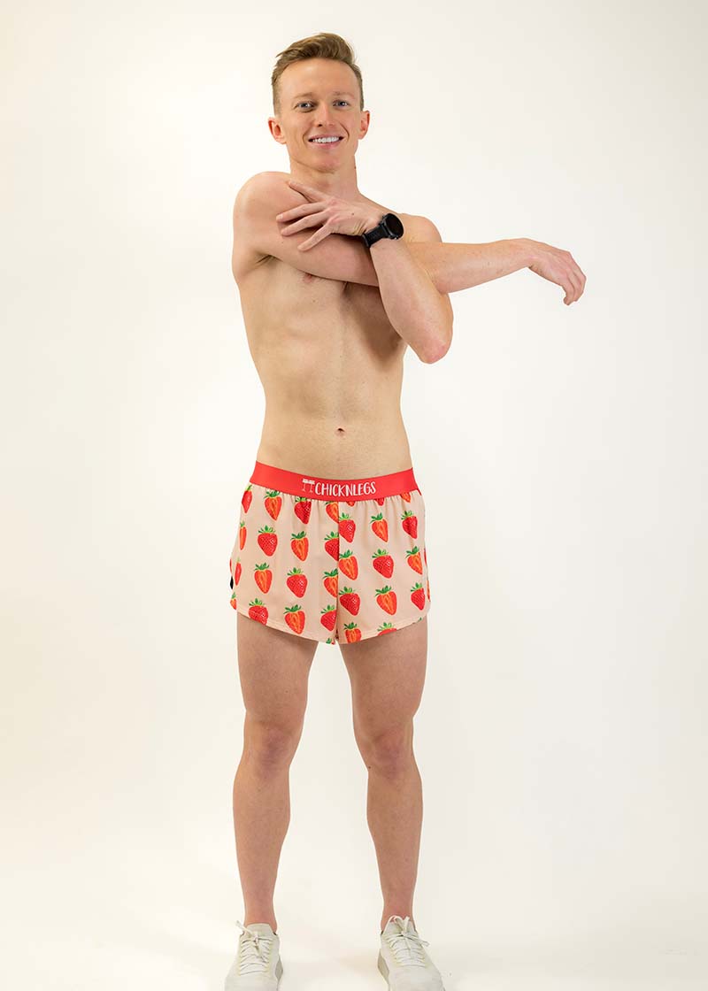 Full body shot of runner stretching while wearing the men's strawberry running shorts.