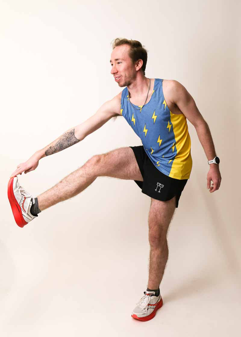 Runner stretching while wearing the ChicknLegs split shorts and blue bolts performance singlet.