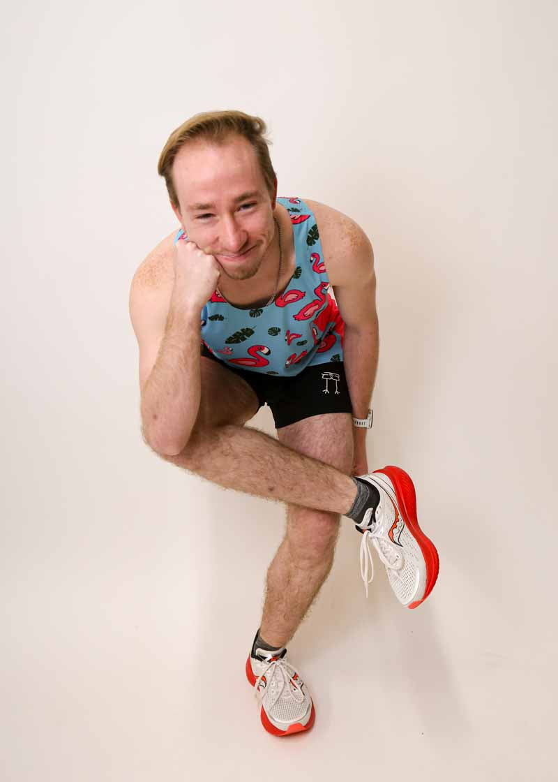 Runner doing a goofy stretch while wearing the ChicknLegs men's blue flamingo singlet.