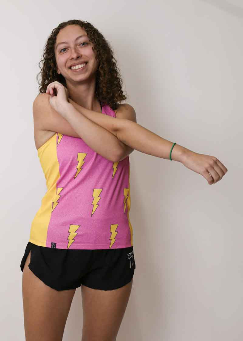 Runner stretching while wearing the women's pink bolts performance singlet.
