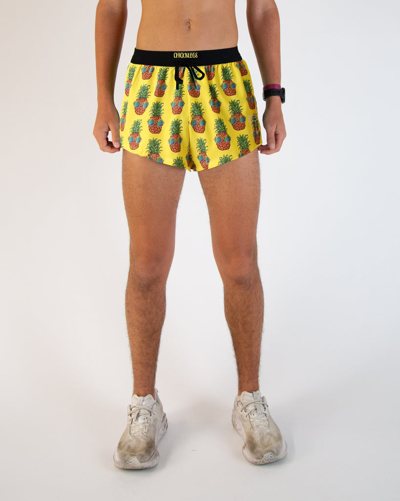 Runner is wearing ChicknLegs in the men's 2 in drawstrings in the split running shorts. The print has fun pineapples with sunglasses on it with a bright yellow background.