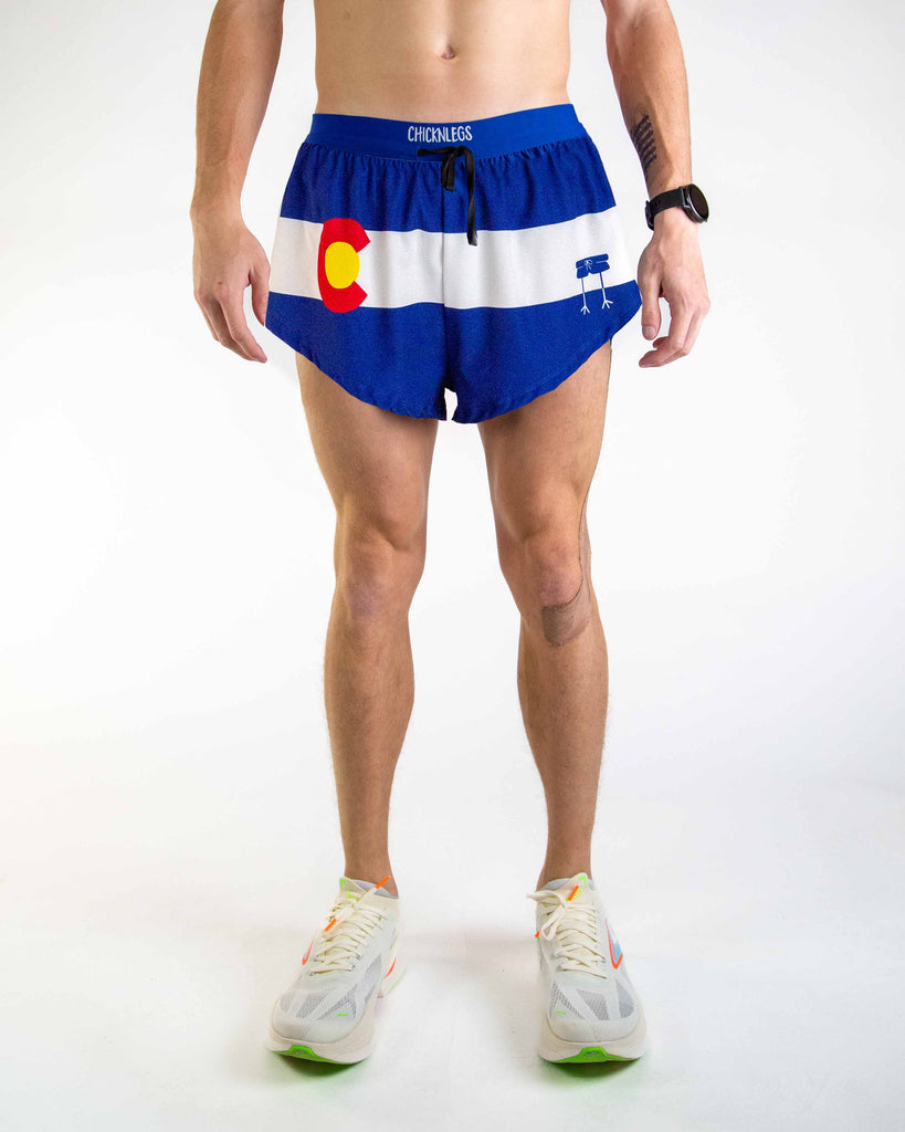 Front view of ChicknLegs Men’s 2-inch DS Split Running Shorts featuring a soft elastic drawstring waistband for a smooth, secure fit and black mesh liner for coverage and breathability. Featured are the Colorado State Flag in red, white, blue and yellow! 