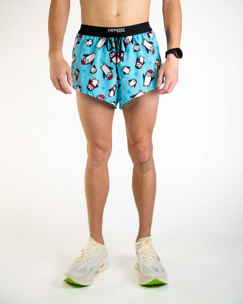Front view of ChicknLegs Men’s 2-inch DS Split Running Shorts featuring a soft elastic drawstring waistband for a smooth, secure fit and black mesh liner for coverage and breathability. Featured in the slippery bois design with penguins and santa hats on a blue background.