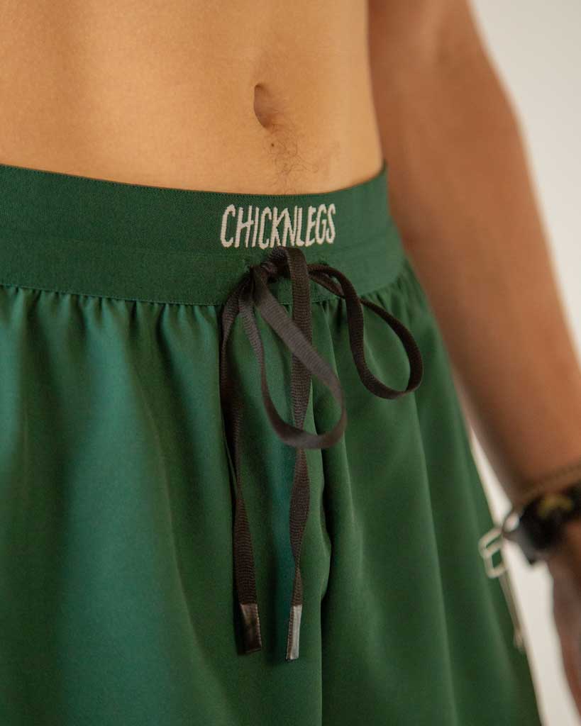 Close-up detail of ChicknLegs men’s 2-inch running shorts, solid forest green color and drawstring waistband.