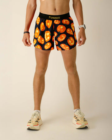 Runner is wearing ChicknLegs in the men's 4 inch split running shorts in the pumpkins design, with black background and soft black waistband with yellow text.