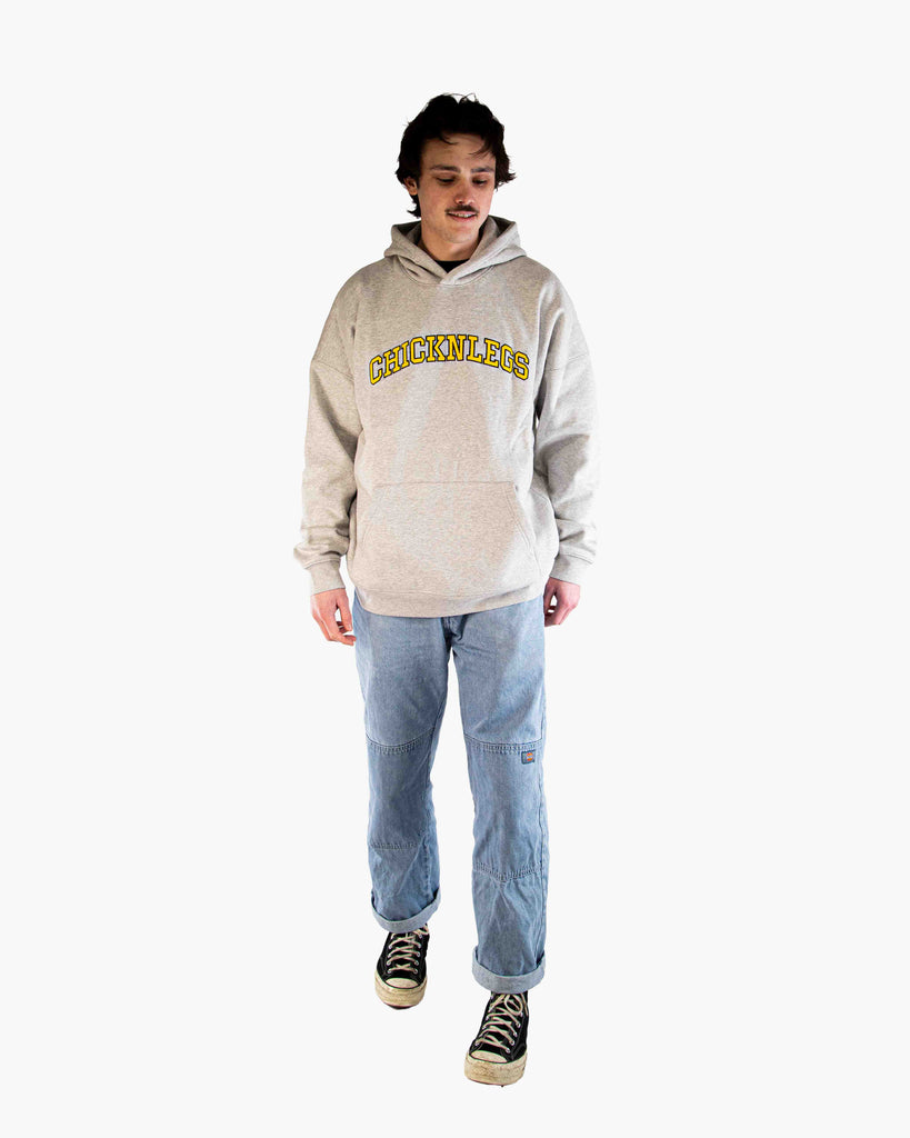 Full body view of model wearing ChicknLegs Varsity Oversized Unisex Hoodie, showing the relaxed loose fit, midweight fabric, and embroidered logo design.