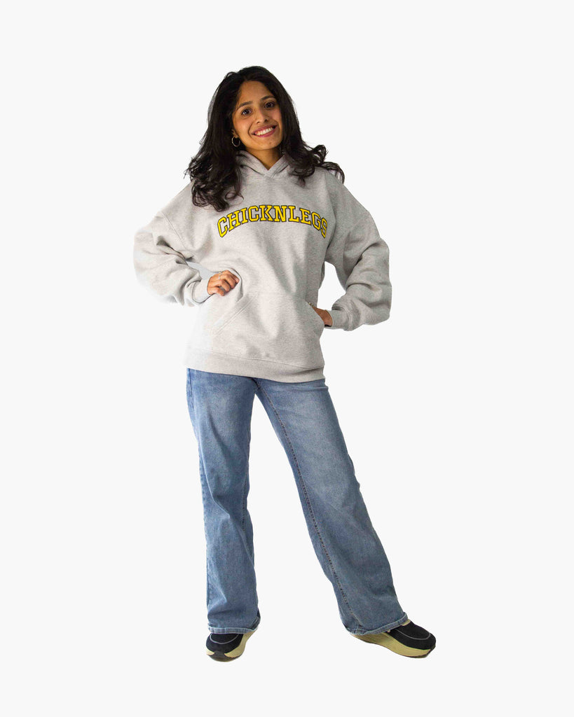 Full body view of model wearing ChicknLegs Varsity Oversized Unisex Hoodie, showing the relaxed loose fit, midweight fabric, and embroidered logo design.