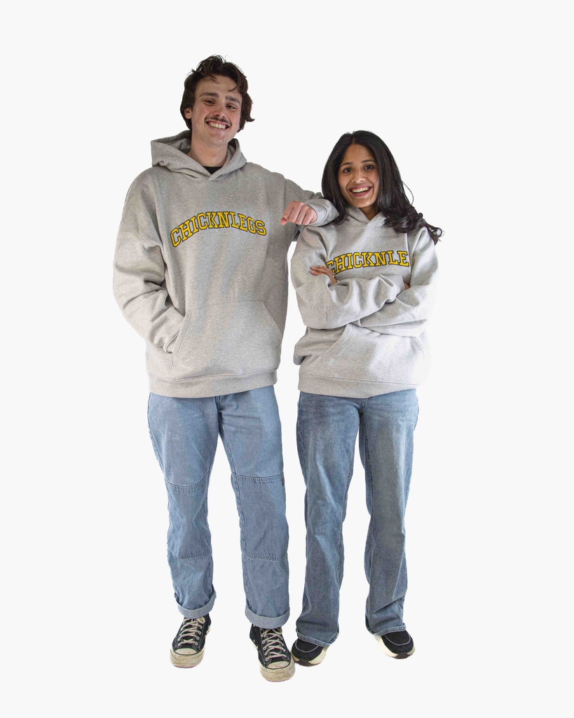 Full body view of models wearing ChicknLegs Varsity Oversized Unisex Hoodie, showing the relaxed loose fit, midweight fabric, and embroidered logo design.