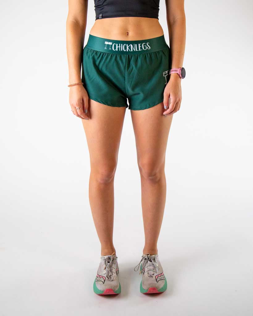 Front view of ChicknLegs women’s 1.5-inch split running shorts in solid forest green design, featuring lightweight fabric, elastic waistband, and breathable liner.