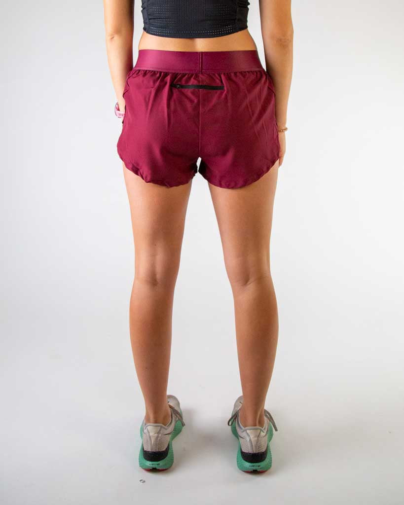 Back view of ChicknLegs women’s 1.5-inch split running shorts in solid maroon, featuring elastic waistband and breathable liner and back zipper pocket.