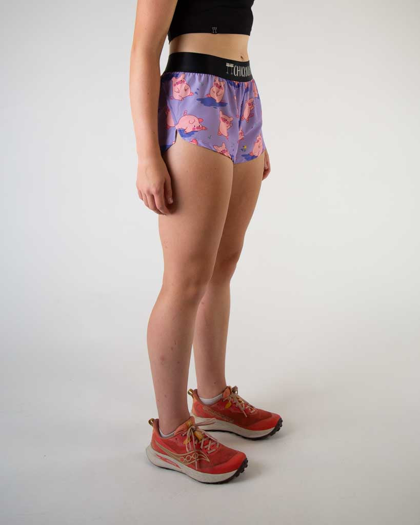 Right side view of ChicknLegs women’s 1.5-inch split running shorts with drawstring, breathable liner, lilac purple background and pink piggies design.