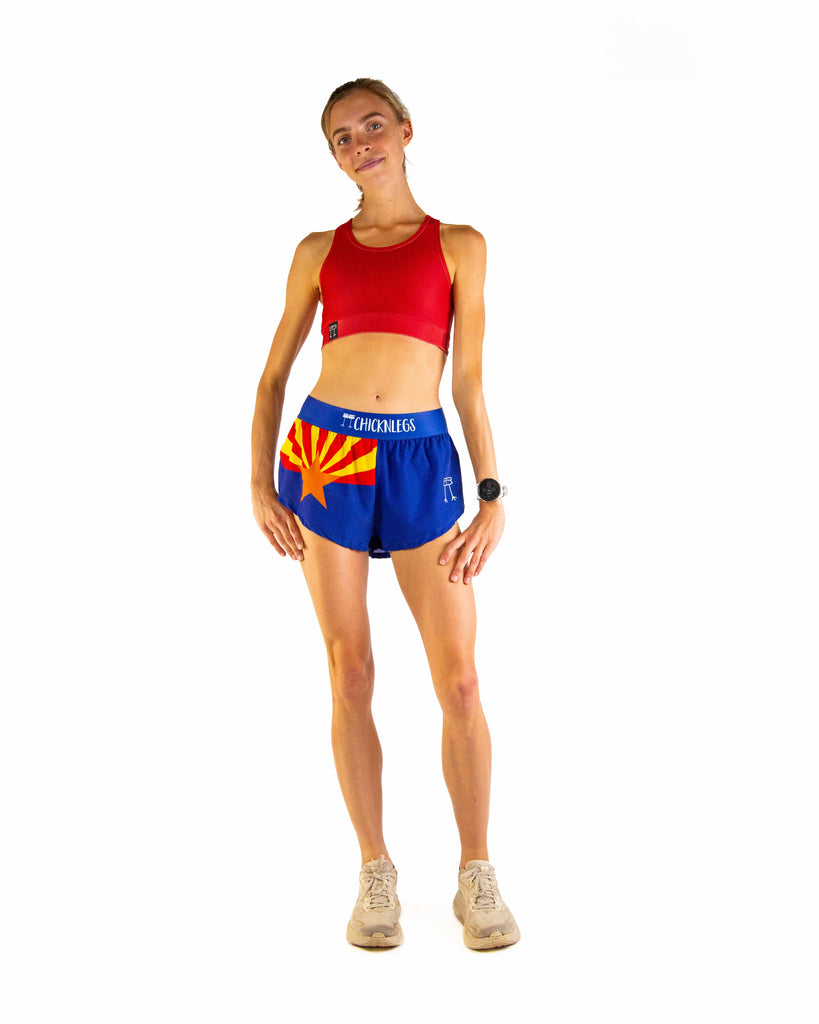 Full body view of model wearing ChicknLegs Women’s 1.5-inch split running shorts featuring the Arizona State Flag paired with the cardinal red sports bra.