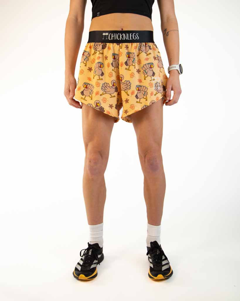 Runner is wearing ChicknLegs in the women's 4 inch split running shorts in the pardoned turkey design. This pattern has thanksgiving turkeys running with fall leaves.