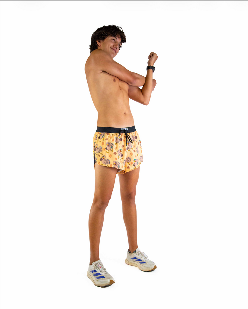 Full body view of model wearing ChicknLegs men’s 2-inch split running shorts in the pardoned turkey design, styled with white running shoes.