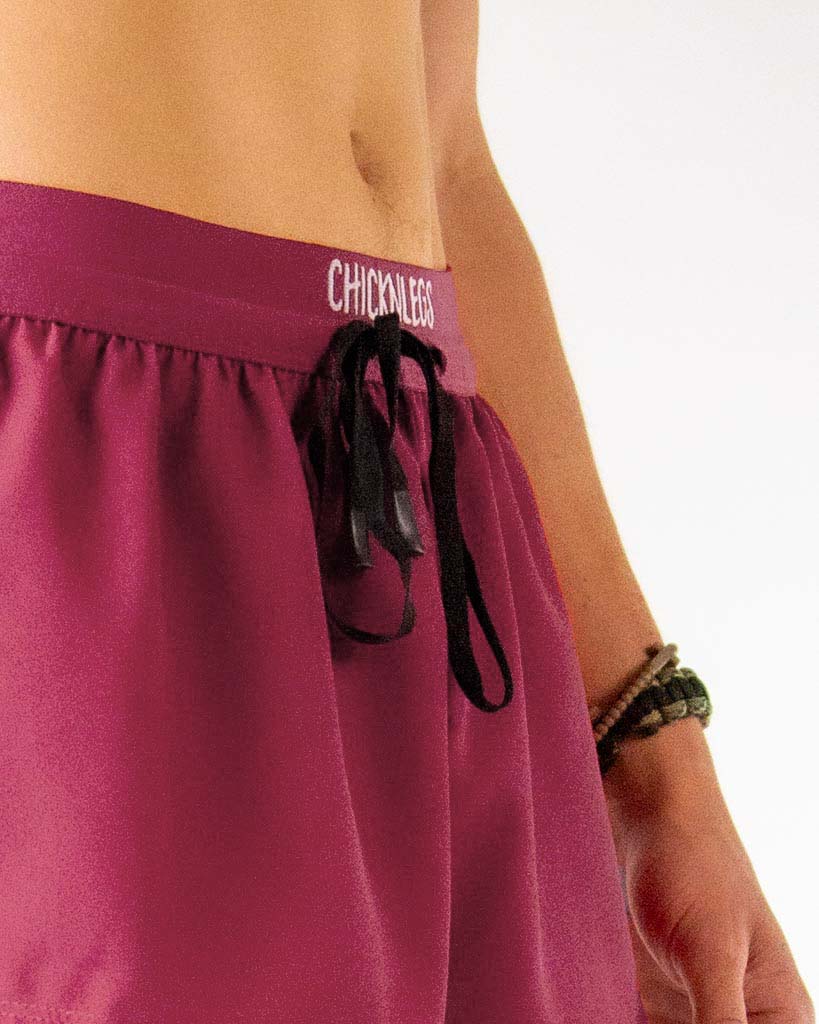 Close up view of ChicknLegs Men's 2-inch DS split running shorts in the maroon solid color, featuring a soft elastic drawstring waistband for a smooth, secure fit.