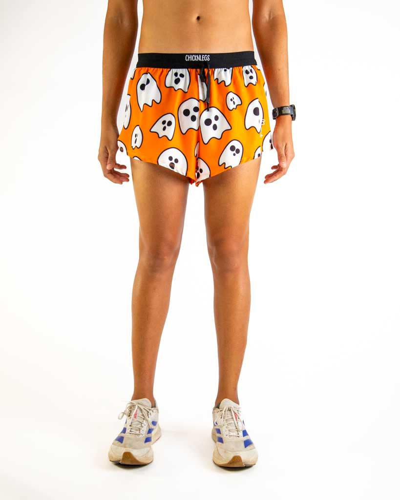 Front view of ChicknLegs men’s 2-inch split running shorts with drawstring, breathable liner, orange background and white ghost design.