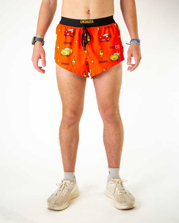 Front view of ChicknLegs men’s 2-inch split running shorts with drawstring, breathable liner, red orange background and yellow lightning bolt design with red and yellow cars.