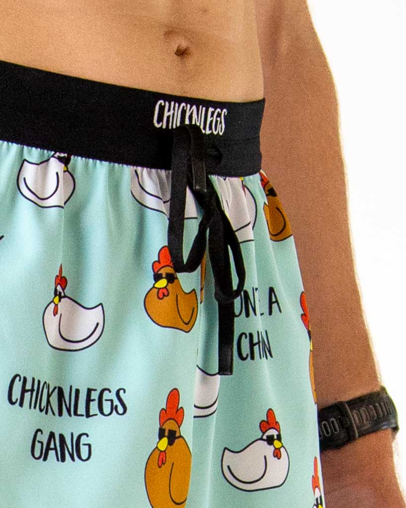 Close-up detail of ChicknLegs men’s 2-inch running shorts, light blue fabric with white and brown pattern and drawstring waistband.
