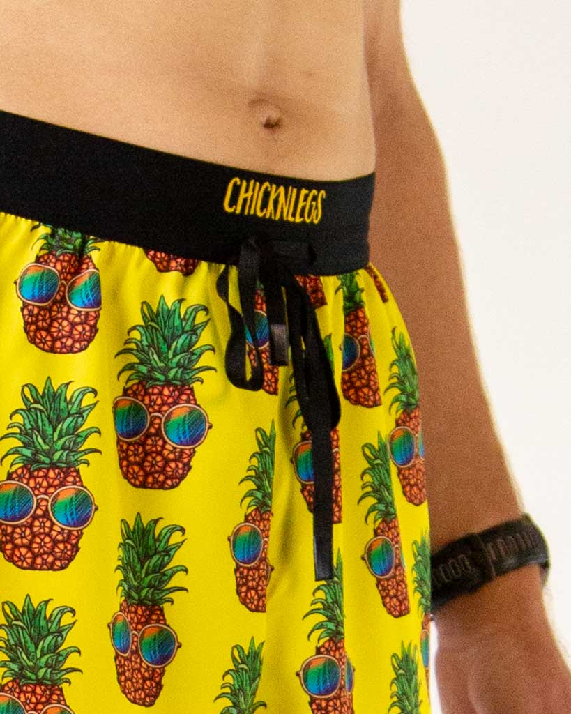 Close-up detail of ChicknLegs men’s 2-inch running shorts, yellow fabric with pineapple pattern and drawstring waistband.