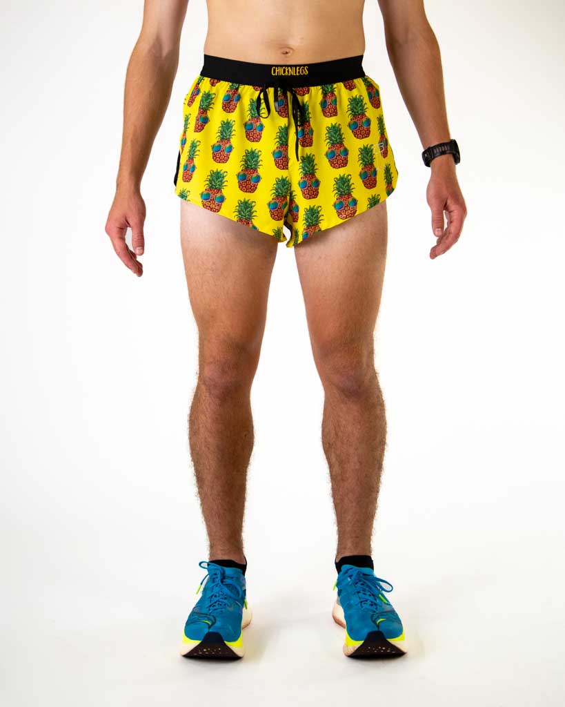 Front view of ChicknLegs men’s 2-inch split running shorts with drawstring, breathable liner, yellow background and pineapple design.