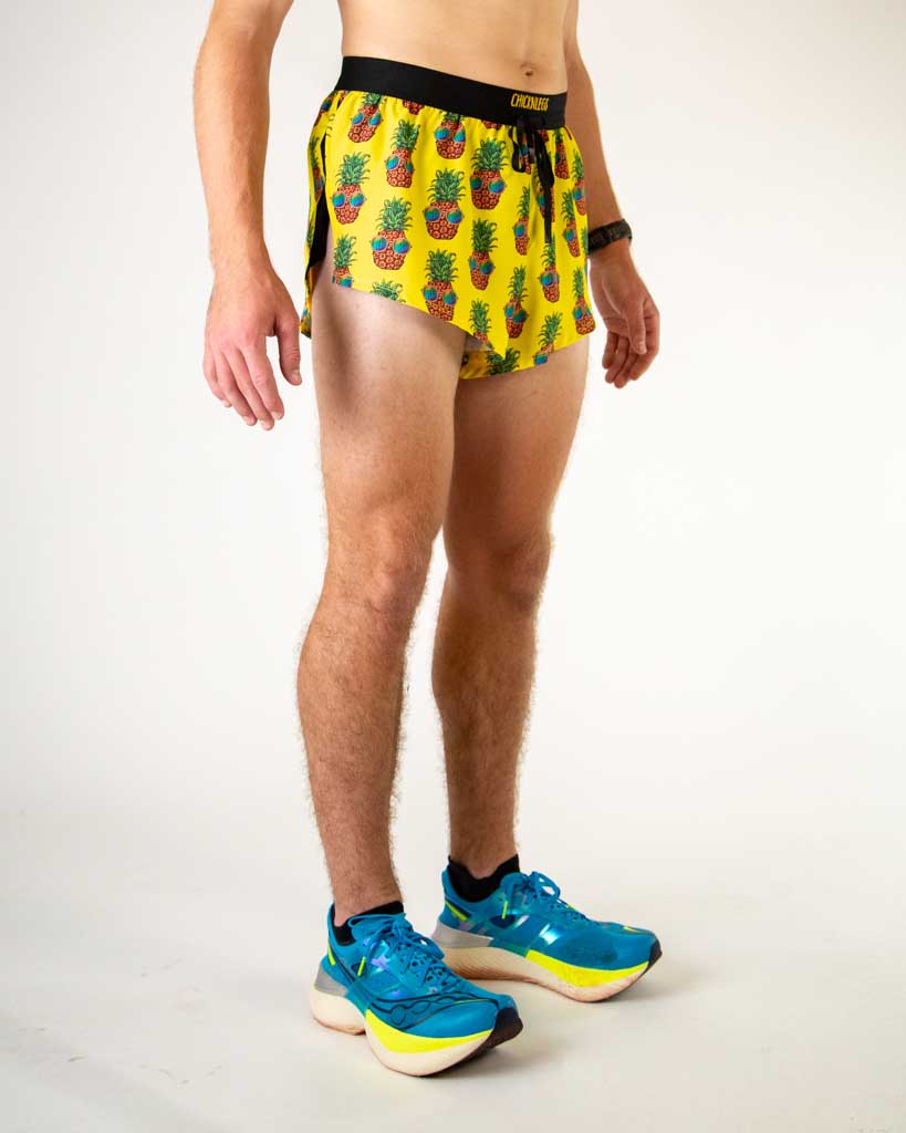 Right side view of ChicknLegs men’s 2-inch drawstrings split running shorts with pineapples with sunglasses and black waistband.