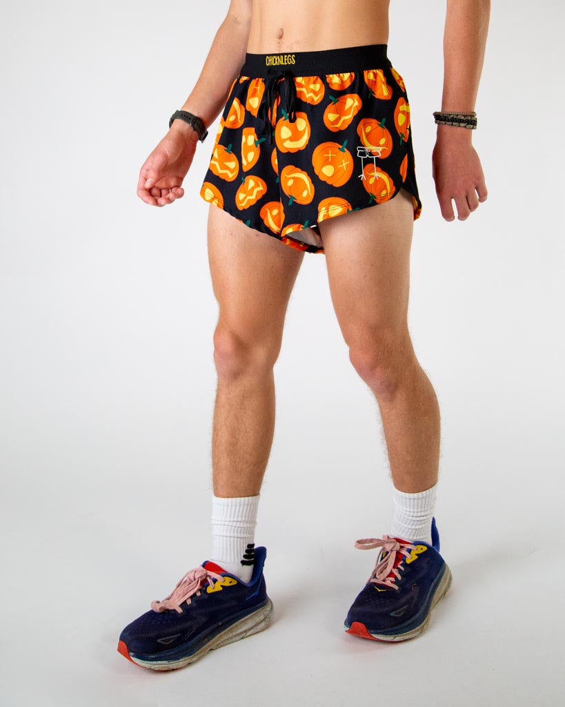 Left side view of ChicknLegs men’s 2-inch split running shorts in black background and orange pumpkins featuring split leg design for running.