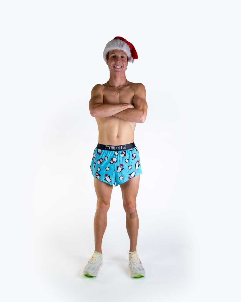 Full body view of model wearing ChicknLegs Men’s 2-inch Split Running Shorts featuring a soft elastic waistband, inner pocket, and black mesh liner for full coverage and breathability featured in the slippery bois penguin santa hats.