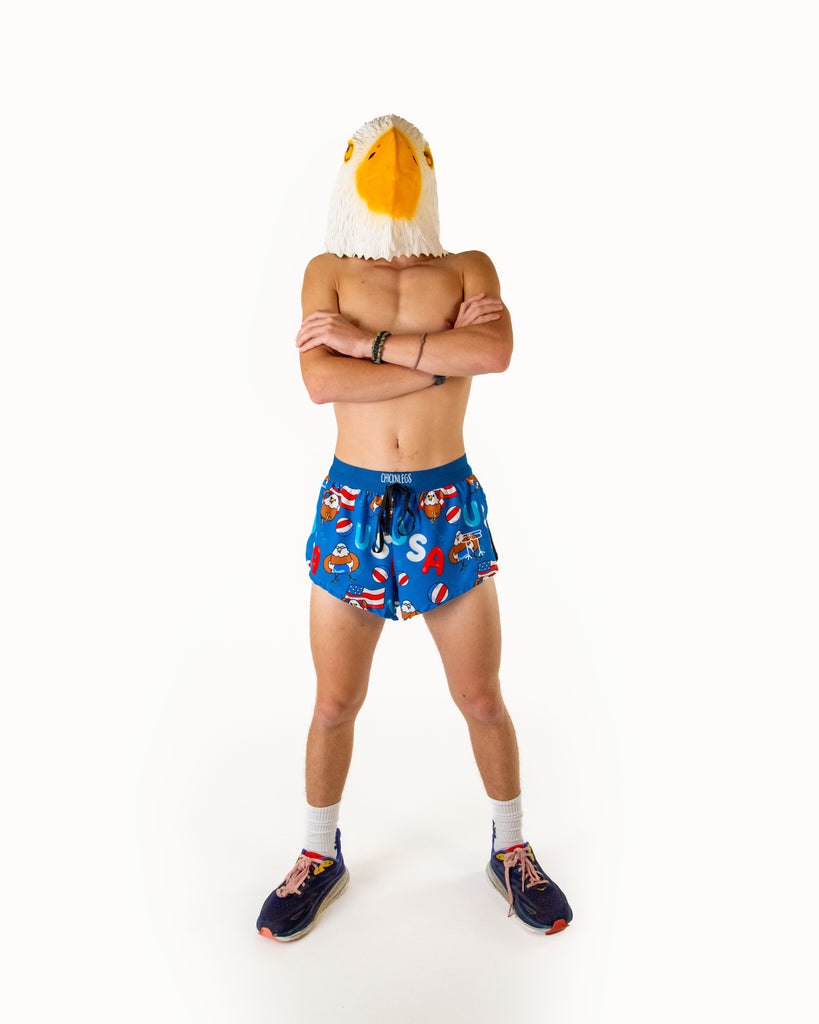 Full body view of model wearing ChicknLegs men’s 2-inch split running shorts in the USA Pool Party design, styled with black running shoes.