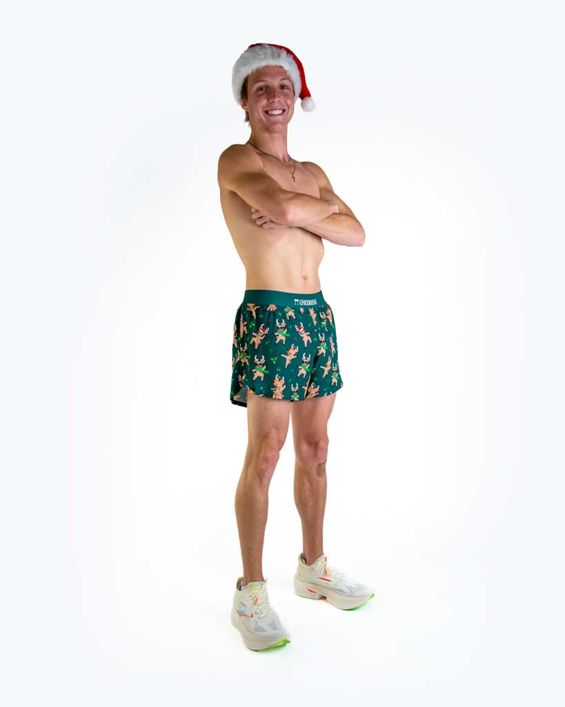 Full body view of model wearing ChicknLegs men’s 4-inch split running shorts featuring a soft elastic waistband, rear zipper pocket, and black mesh liner for full coverage and breathability. Featured is the rockin reindeer in santa hats, scarves and christmas lights.