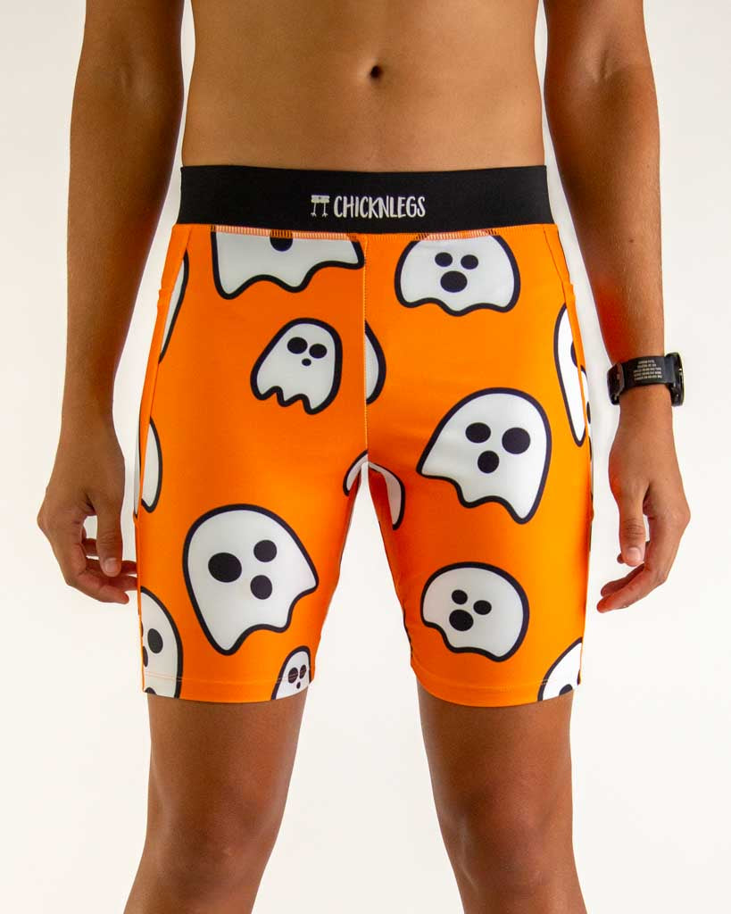 Close-up detail of ChicknLegs Men’s 8-inch Half Tights fabric and construction, featuring the soft elastic waistband, internal key pocket, and breathable black mesh liner. The print featured are the Ghosts that have an orange background and black waistband.
