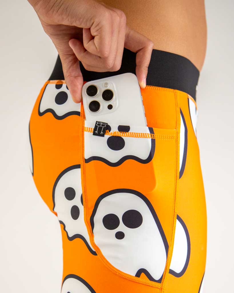 A close up shot is shown of ChicknLegs men's 8 inch half tight pocket. Model is holding a phone and placing it into the pocket to show the smooth fit.