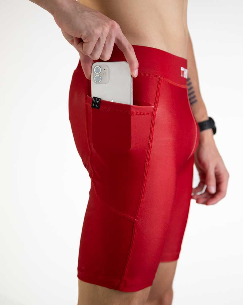 Close-up detail of ChicknLegs Men’s 8-inch Half Tights fabric and construction, featuring the soft elastic waistband with side pockets Runner is placing phone into side pocket to demonstrate the fit.