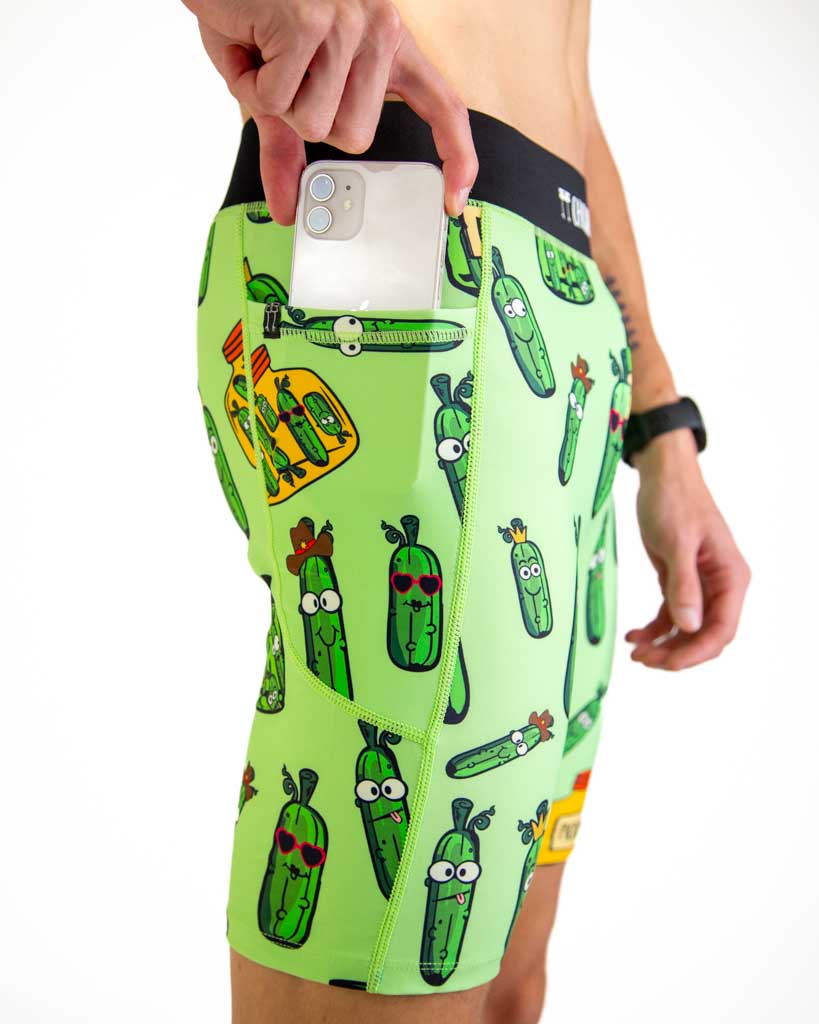 Close-up detail of ChicknLegs Men’s 8-inch Half Tights fabric and construction, featuring the soft elastic waistband, internal key pocket, and side pockets. Runner is placing phone in the pocket to demonstrate the fit.