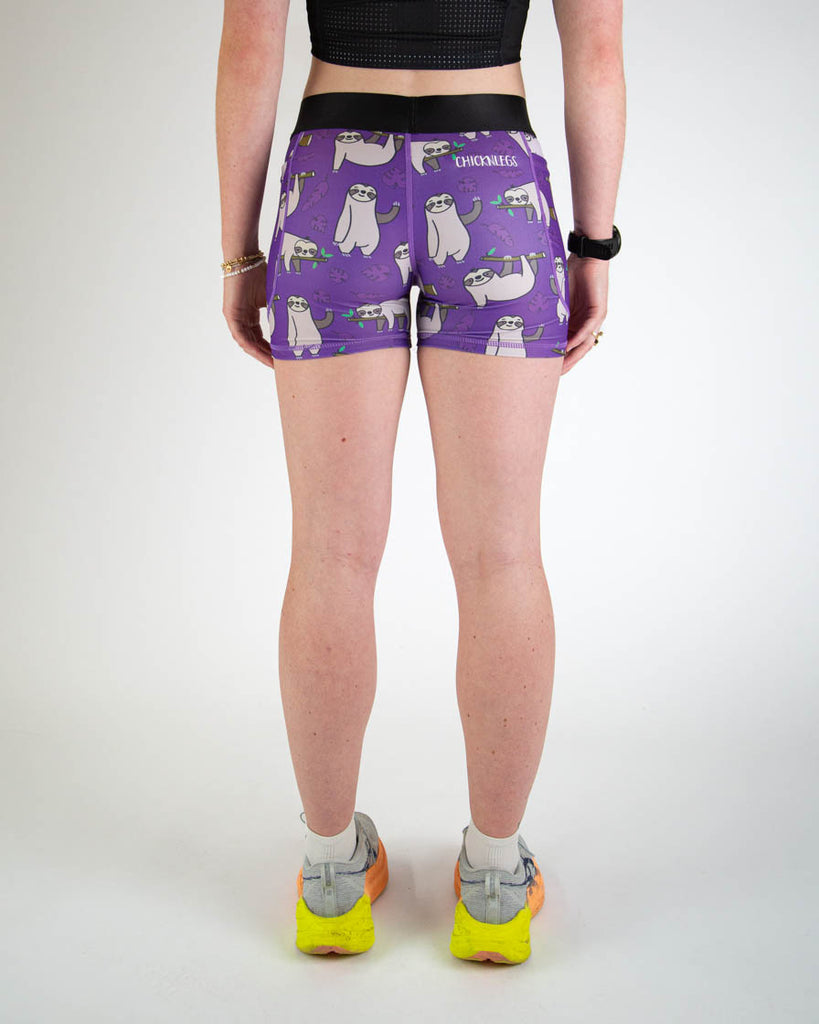 Back view of ChicknLegs women’s 3-inch compression spandex running shorts with a purple background and sloths all over.