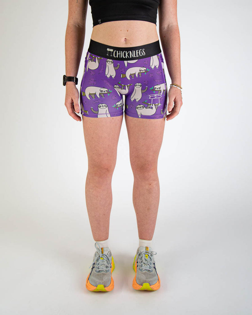 Front view of ChicknLegs women’s 3-inch compression spandex running shorts, purple background and sloths all over.