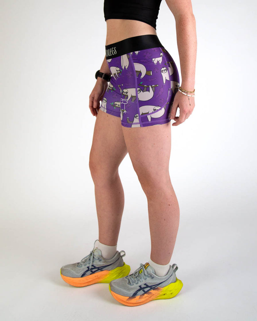 Left view of ChicknLegs women’s 3-inch compression spandex running shorts, purple background and sloths all over, showing side pockets.