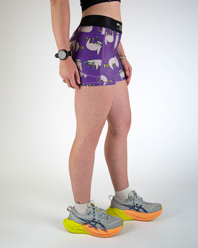 Right view of ChicknLegs women’s 3-inch compression spandex running shorts, purple background and sloths all over, showing side pockets.