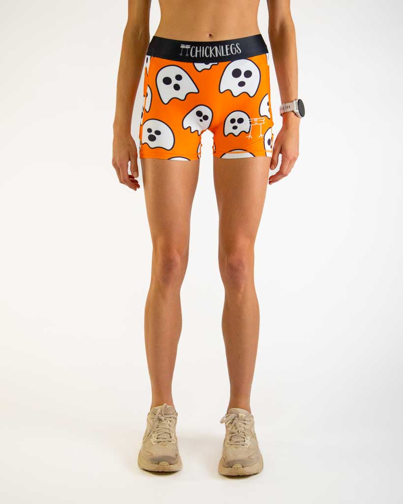 Front view of ChicknLegs Women’s 3-inch compression shorts featuring a soft elastic waistband for a smooth, secure fit and spandex-polyester blend fabric for ultimate comfort. Featured design is the ghosts with an orange background and black waistband.