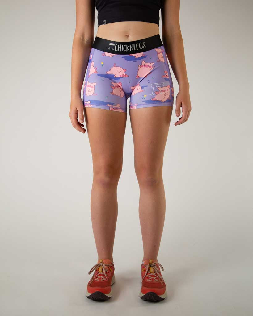 Front view of ChicknLegs women’s 3-inch compression spandex with side pockets, lilac purple background and pink piggies design.