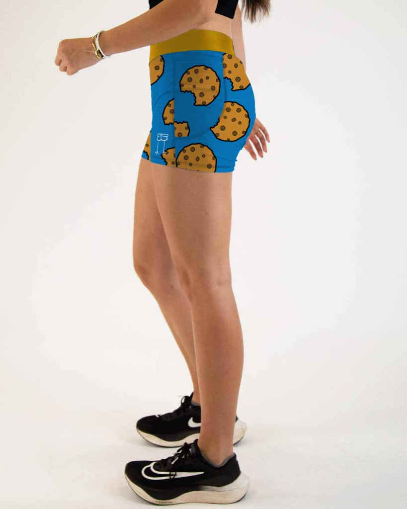 Runner is wearing ChicknLegs in the women's 3 in compression spandex with pockets shorts in the chocolate chip cookies design. The print has chocolate chip cookies on it with a blue background.