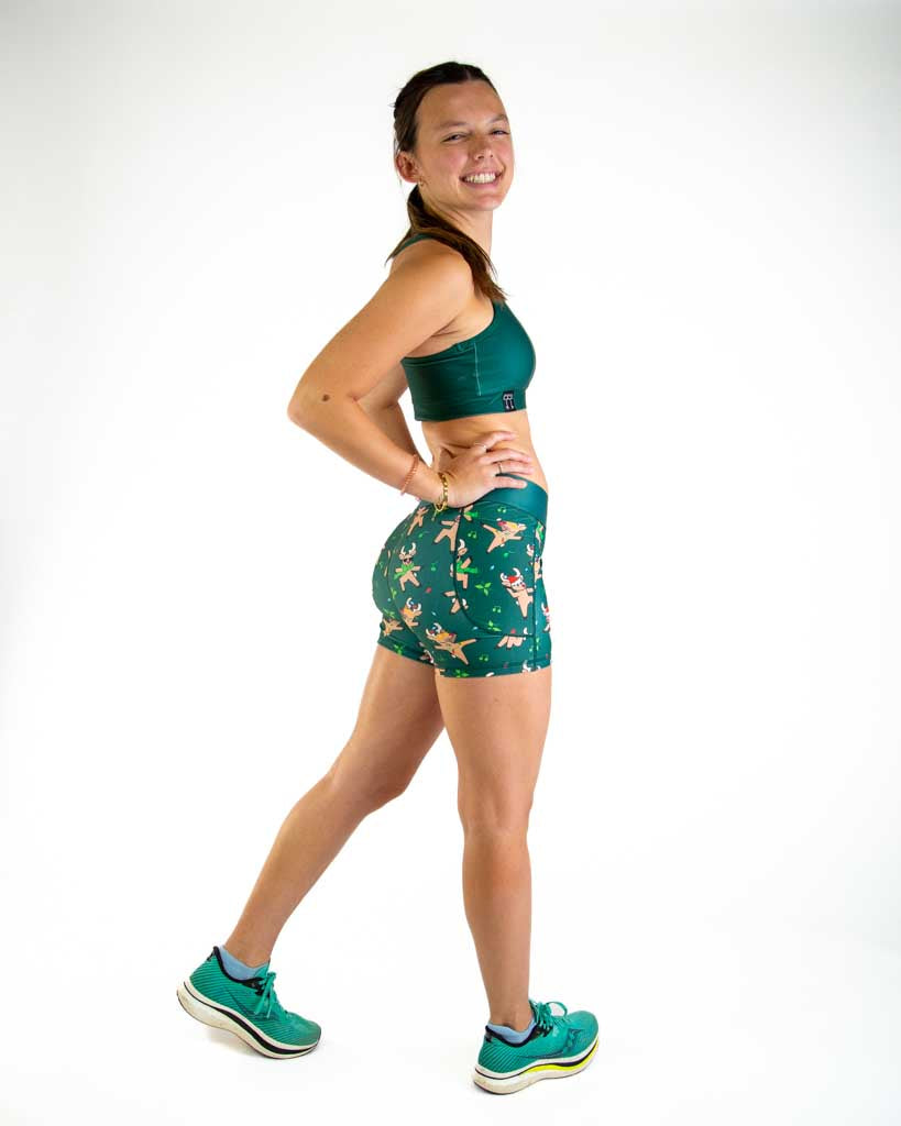 Full body view of model wearing ChicknLegs Women’s 3-inch compression shorts featuring a soft elastic waistband, dual side pockets, and spandex-polyester fabric for a supportive, chafe-free fit. Featured are the Rocking Reindeer in the christmas lights and santa hats.