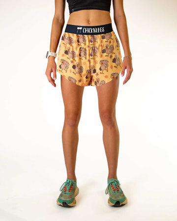 Runner is wearing ChicknLegs in the women's 4 inch split running shorts in the pardoned turkey design. This pattern has thanksgiving turkeys running with fall leaves.