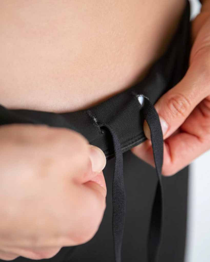 A close up image is shown of the runner holding the drawstrings out for the photo. 