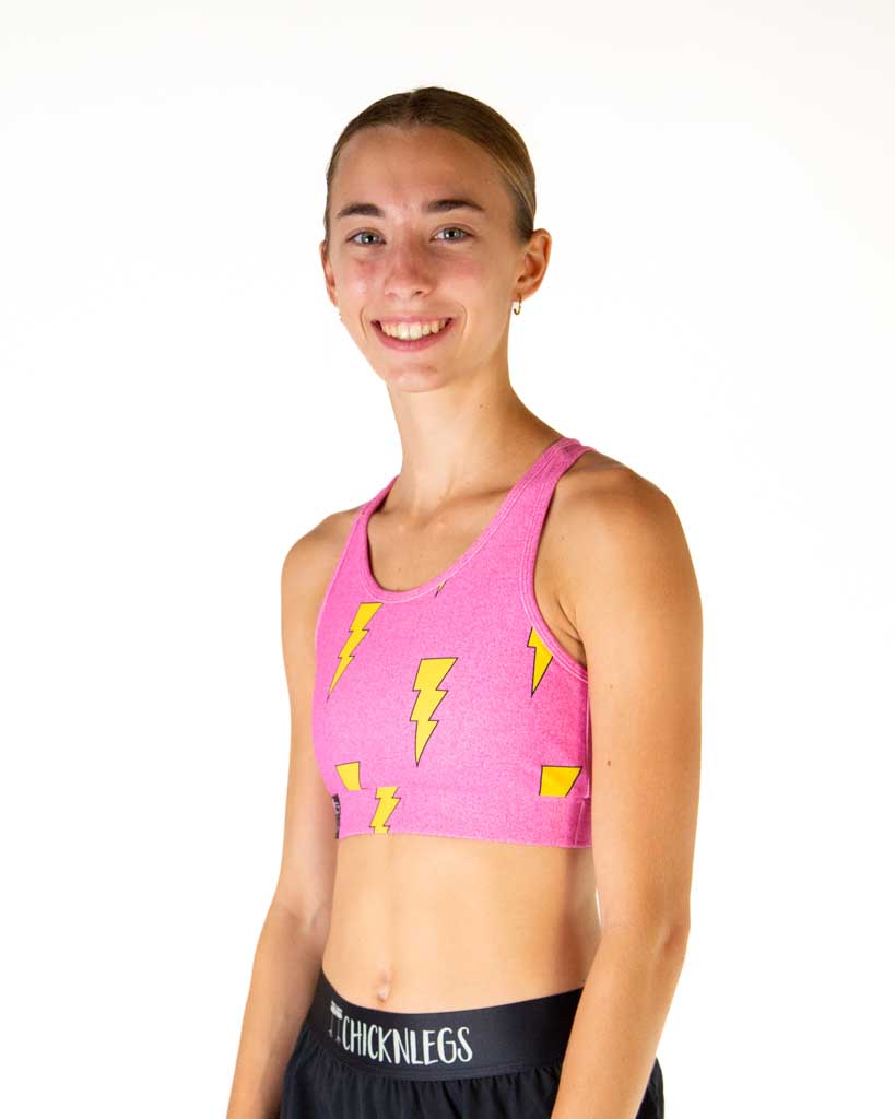 Left side view of ChicknLegs women’s OG sports bra in hot pink with yellow lightning bolts, showing the side strap. 