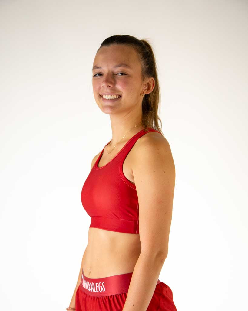 Left side view of ChicknLegs women’s og sports bra in solid cardinal red, showing racerback strap and supportive fit.
