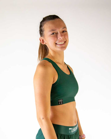Right side view of ChicknLegs women’s OG sports bra in forest green color and elastic underband.