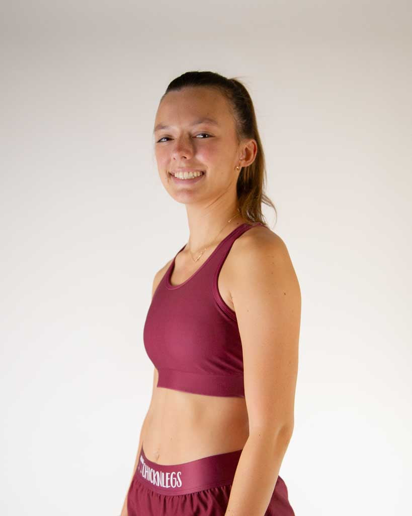 Left side view of ChicknLegs women’s OG sports bra in solid maroon, showing racerback strap and supportive fit.