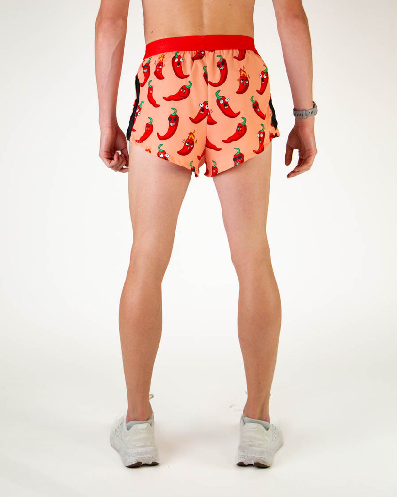 Back view of ChicknLegs men’s 2-inch split running shorts in orange with red chili peppers and red waistband.