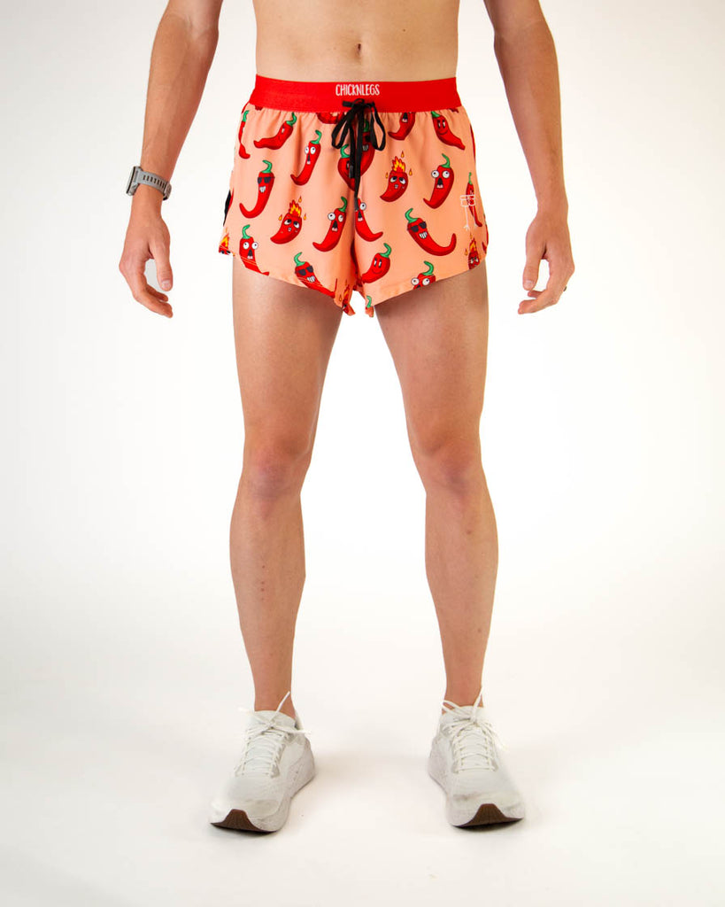 Front view of ChicknLegs men’s 2-inch split running shorts with drawstring, breathable liner, orange background and red chili pepper design.