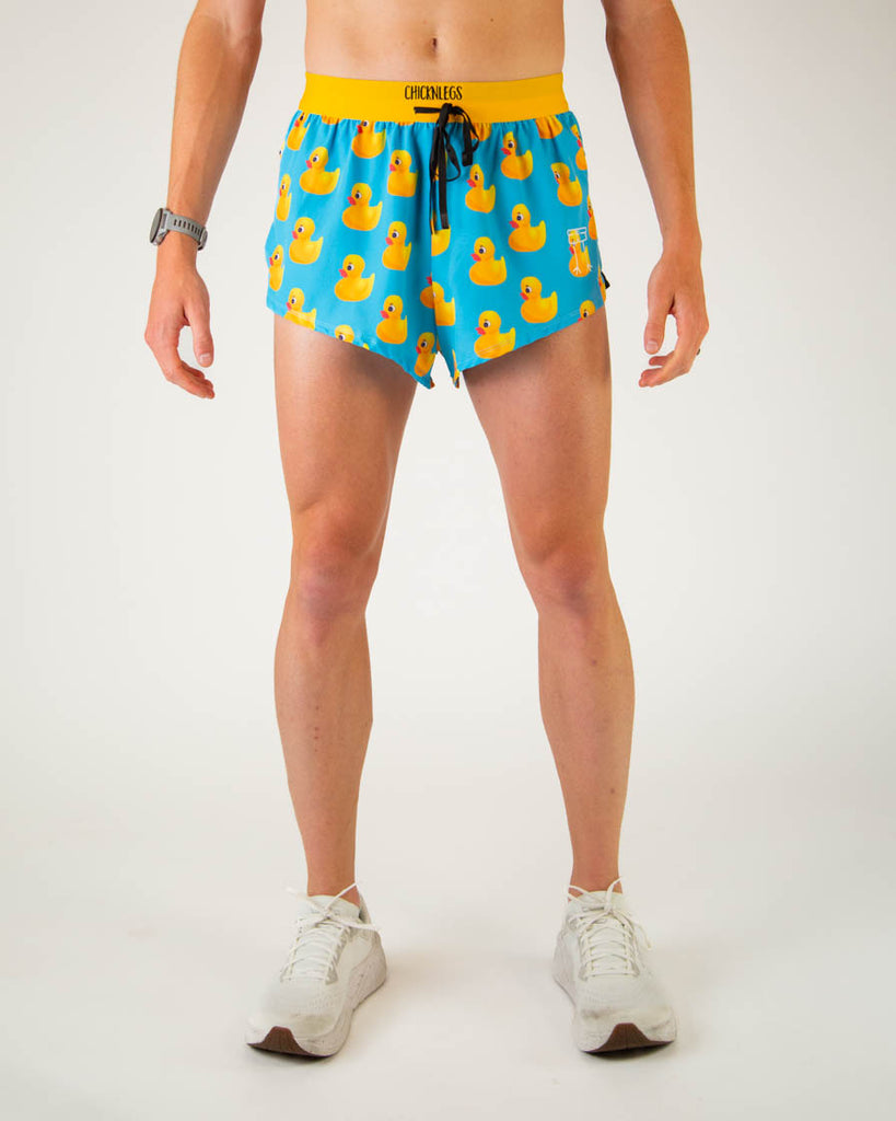 Front view of ChicknLegs men’s 2-inch split running shorts with drawstring, breathable liner, blue background and yellow rubber ducky design with a yellow waistband.